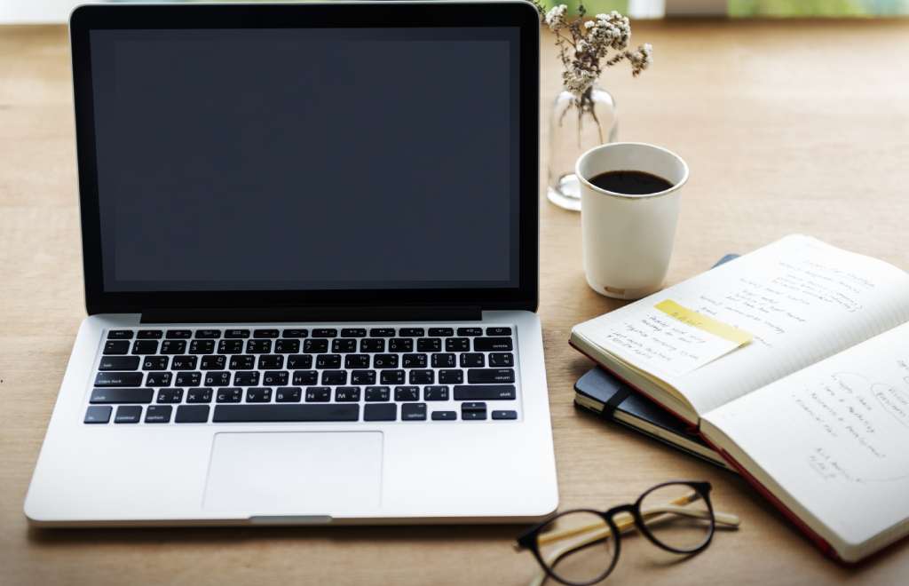 laptop and a notebook on a table with project management material