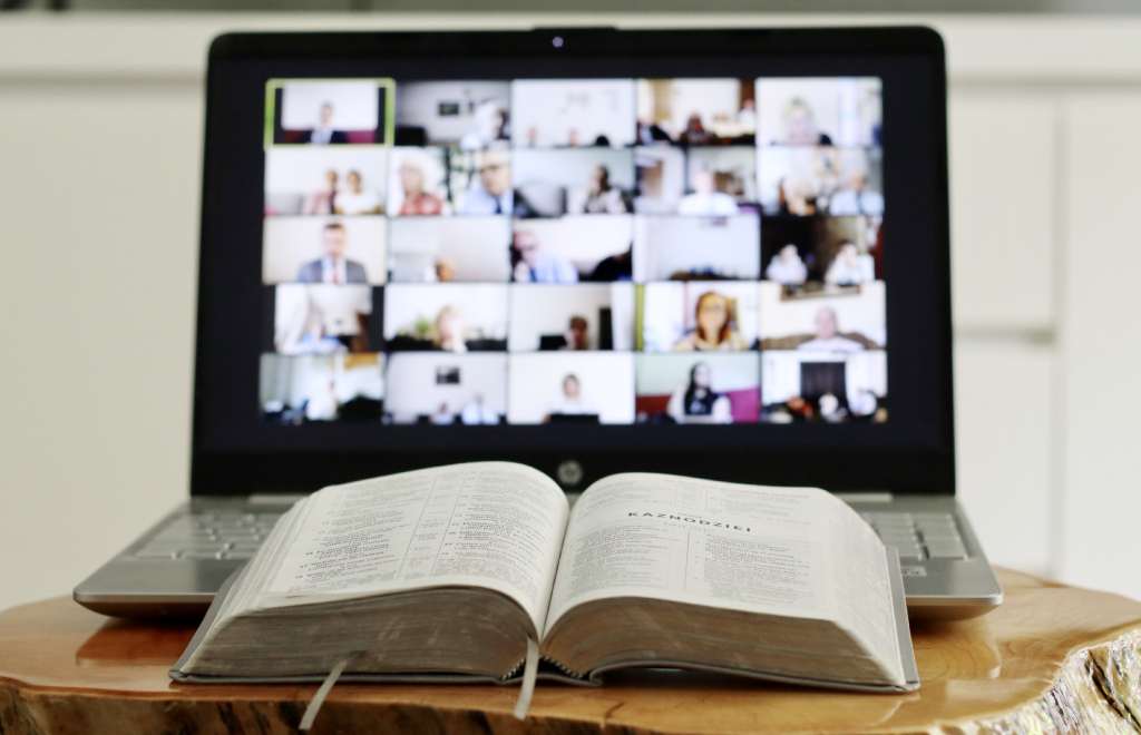 A person with a book and a computer on a table having online classes in project management